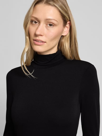 Vrouwenmodel draagt Longsleeve met rolkraag van Marc Cain, effen design, materiaalmix met stretch, nauwsluitend model, nahaufnahme bovenlichaam.