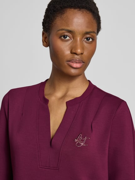 Frauenmodel trägt Regular Fit Minikleid aus Viskose-Mix Modell 'Abito' von Liu Jo in Dunkellila mit Ziersteinbesatz, Nahaufnahme Oberkörper.