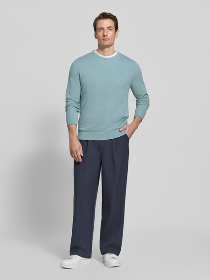 Männermodel trägt Regular Fit Strickpullover aus reiner Baumwolle mit Label-Detail von LERROS in Hellblau, kombiniert mit dunkelblauer Hose, elastische Abschlüsse, Ganzkörperansicht von vorne.