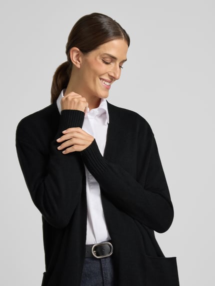 Frauenmodel trägt Relaxed Fit Strickjacke aus Viskose-Mix mit Eingrifftaschen von Christian Berg Woman, schwarze Farbe, gerippte Abschlüsse, Nahaufnahme Oberkörper, Damen Strickjacke, langärmliges Design