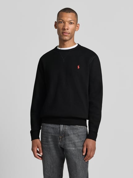 Männermodel trägt Regular Fit Sweatshirt aus Baumwoll-Mix von Polo Ralph Lauren in Schwarz mit rotem Logo, Ganzkörperansicht von vorne. Herren Sweatshirt
