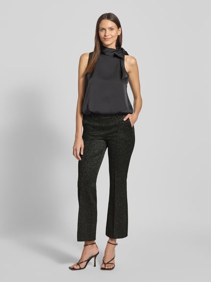 Vrouwenmodel draagt Stoffhose in verkürzter Passform Modell 'FRANCOISE' van Cambio, zwart met glittereffect, rechte snit, elastische tailleband, Franse steekzakken, verkorte pasvorm, gemengd materiaal met viscose, volledige lichaamsopname van voren.