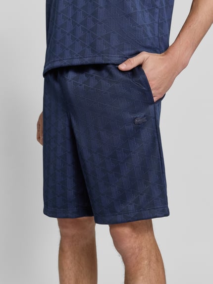 Männermodel trägt Regular Fit Sweatshorts mit Tunnelzug von Lacoste in Dunkelblau mit geometrischem Muster, Nahaufnahme Oberschenkel