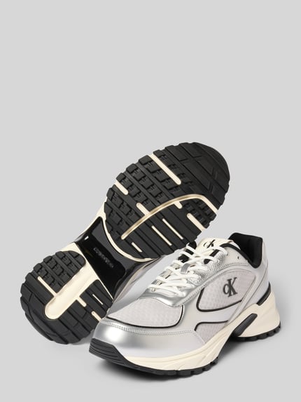 Produktfoto, Sneaker mit Label-Detail von Calvin Klein Jeans im Material-Mix, abgerundete Spitze, Schnürverschluss, strukturierte Sohle, Absatzhöhe 3 cm, Schafthöhe 4 cm, Schaftweite 6 cm, überwiegend helle Farben mit schwarzen Akzenten.