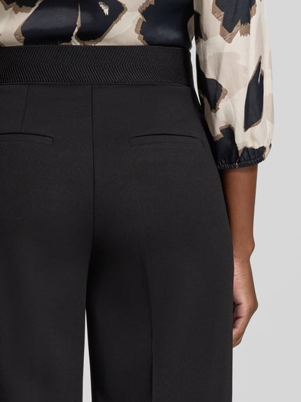 Frauenmodel trägt Regular Fit Weite Hose mit Bügelfalten Modell 'LT JULI' von Betty Barclay, schwarze Farbe, Detailaufnahme Rückansicht, Damen Weite Hose von Betty Barclay.