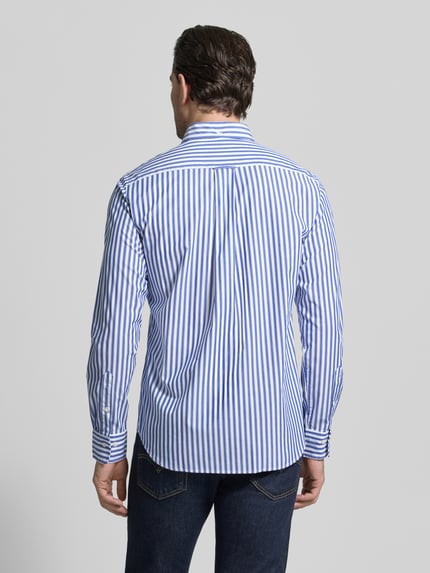 Männermodel trägt blauw-wit gestreept Slim Fit Freizeithemd met borstzak van Gant, puur katoen, lange mouwen, ruglengte M 77 cm, schouderbreedte 46 cm, mouwlengte 65 cm, gestikt logo, button-downkraag, afgeronde zoom, doorlopende pasvorm. Ganzkörperansicht Rückansicht.