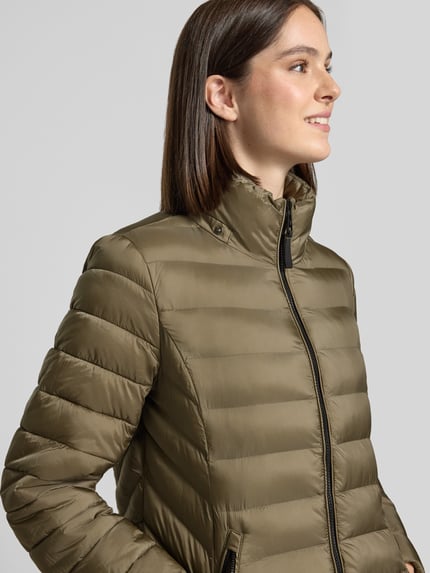 Frauenmodel trägt Steppjacke mit Zweiwege-Reißverschluss von FUCHS SCHMITT in Khaki, glatte Textur, Nahaufnahme Oberkörper. Slim Fit, Kapuze, Reißverschlusstaschen, Rückenlänge 83 cm, Schulterbreite 42 cm, Brustweite 51 cm, Ärmellänge 64 cm.