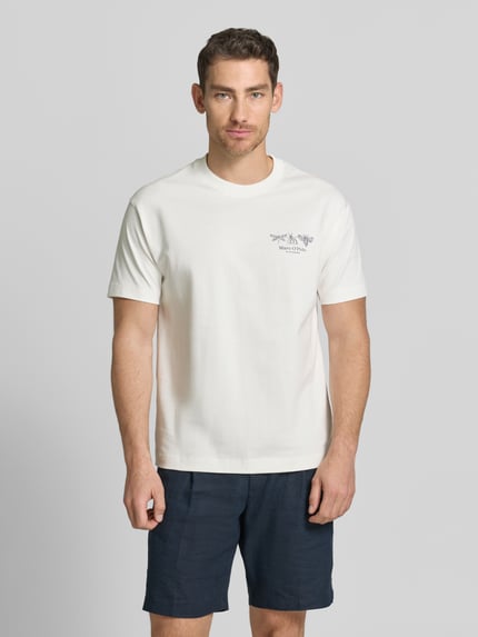 Męski model nosi Relaxed Fit T-Shirt aus reiner Baumwolle von Marc O'Polo, efekt: jednolity kolor, krój regular fit, aplikacja: nadruk z logo i nadruk z motywem, okrągły dekolt, rękaw: krótki rękaw, wykończenie materiału: dżersej, materiał: czysta bawełna, kolor jasny, gładka faktura, Ganzkörperansicht von vorne.