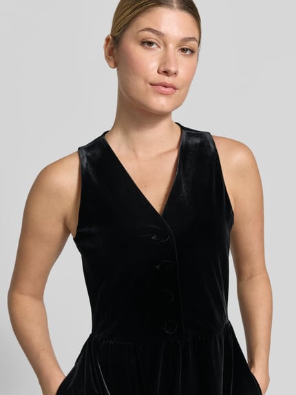 Kobiece modelka nosi Jumpsuit mit V-Ausschnitt und Knopfleiste od Armani Exchange, Aksamit, Mieszanka materiałów z dodatkiem streczu, krój regular fit, kolor czarny, dekolt w serek, listwa guzikowa, Szerokość w rozmiarze S: 41 cm, Długość tyłu w rozmiarze S: 39 cm, całkowita długość w rozmiarze S: 79 cm, Długość wewnętrzna nogawki w rozmiarze S: 8 cm, zbliżenie na górną część ciała