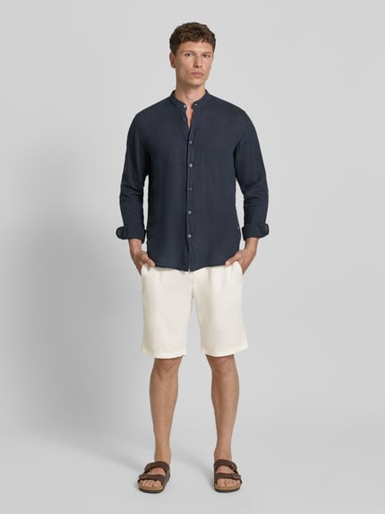 Männermodel trägt Tapered Chinoshorts aus Leinen-Mix Modell 'DS_3S' von BOSS Orange in Creme mit Label-Patch und Flammgarn-Struktur, Ganzkörperansicht von vorne.