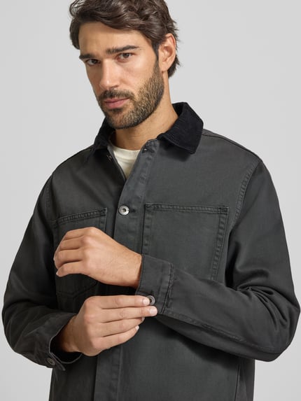Männermodel trägt Regular Fit Overshirt mit Kentkragen Modell 'Corduroy' von Lindbergh, czarna bawełna, Listwa guzikowa, kieszenie na piersi, Długość tyłu w rozmiarze M: 69 cm, Ganzkörperansicht von vorne