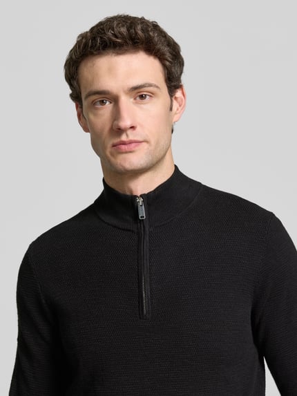 Männermodel trägt schwarzen Slim Fit Strickpullover aus Baumwoll-Mix mit Troyer-Kragen von Profuomo, Nahaufnahme Oberkörper. Rückenlänge 69 cm, Ärmellänge 70 cm, elastische Abschlüsse.