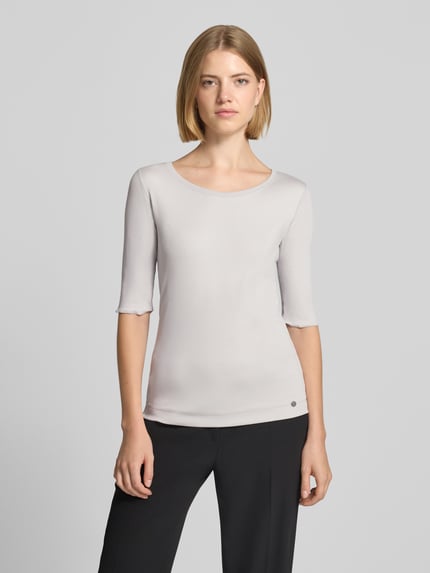 Frauenmodel trägt T-Shirt mit Rundhalsausschnitt und Label-Detail von Marc Cain im Slim Fit aus Baumwoll-Elasthan-Mix, Ganzkörperansicht von vorne.
