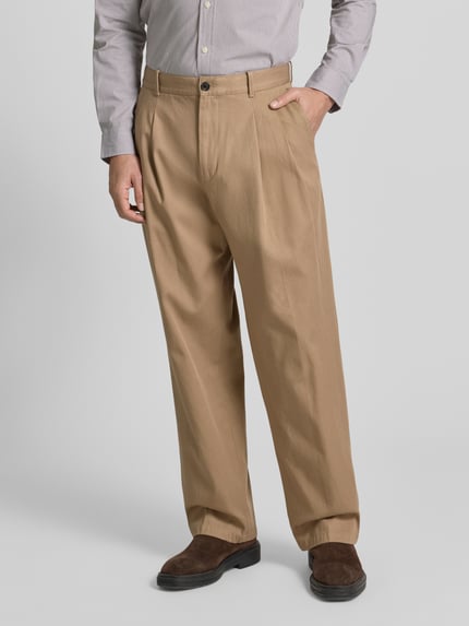 Männermodel trägt Wide Fit Bundfaltenhose aus reiner Baumwolle von Tommy Hilfiger in Beige, 5-Pocket-Design, Mid Waist, Nahaufnahme Oberkörper.