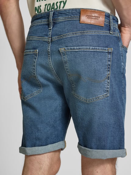 Männermodel trägt Regular Fit Jeansshorts mit Umschlag Modell 'RICK' von Jack & Jones aus Baumwoll-Elasthan-Mix, Eingrifftaschen, Rückansicht Ganzkörperansicht.