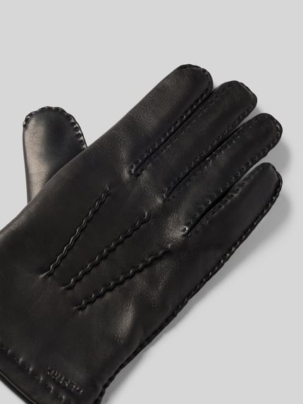 Productfoto, zwarte Hestra handschoen van echt leer met deelnaad, labeldetail, Handschoenen uit echt leer model 'Edward' van Hestra, textuur zichtbaar