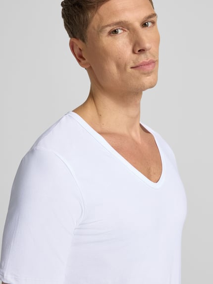 Męski model nosi T-shirt z dekoltem w serek od MCNEAL, mieszanka bawełny ze streczu, krój regular fit, szwy działowe, zbliżenie na górę ciała.