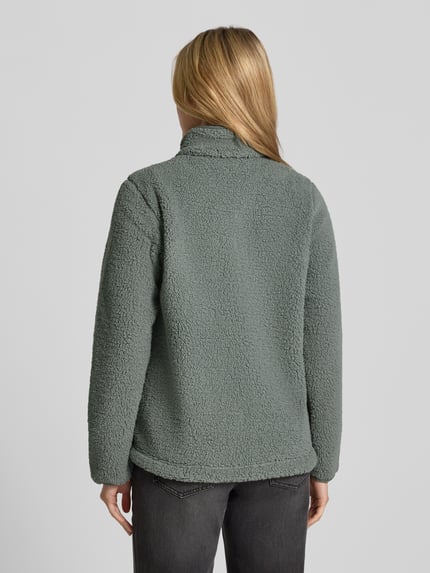 Frauenmodel trägt Fleecejacke mit Stehkragen und Label-Detail von Columbia, Farbe grün, strukturierte Oberfläche, Ganzkörperansicht Rückansicht. Damen Fleecejacke, Regular Fit, Reißverschluss, Eingrifftaschen, Rückenlänge 65 cm, Schulterbreite 41 cm, Brustweite 50 cm, Ärmellänge 64 cm.