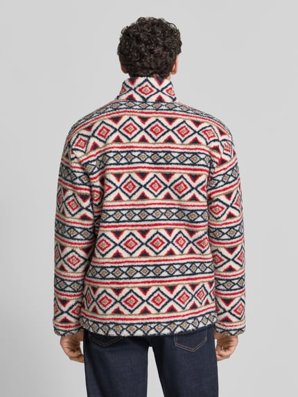 Männermodel trägt Regular Fit Fleecejacke mit Stehkragen von MCNEAL, Teddyfell, Allover-Look in Rot, Weiß und Dunkelblau, Ganzkörperansicht Rückansicht.