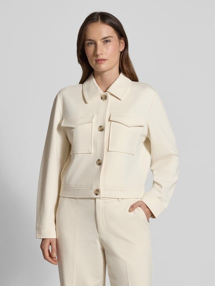 Frauenmodel trägt Relaxed Fit Hemdjacke mit Viskose-Anteil von s.Oliver RED LABEL in Creme mit Umlegekragen und Brustpaspeltaschen, Nahaufnahme Oberkörper.