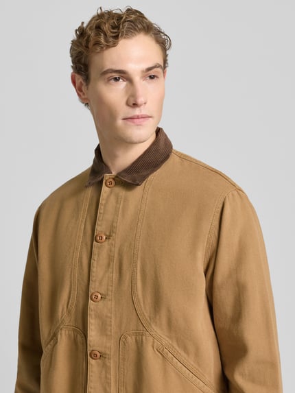 Męskimodel nosi Hemdjacke mit Kentkragen od Forét z bawełny ekologicznej, krój regular fit, listwa guzikowa, wpuszczane kieszenie, długość tyłu 63 cm, rozmiar M, zbliżenie na górną część ciała.