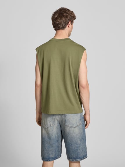 Männermodel trägt Muskelshirt mit Logo und Rundhalsausschnitt von REVIEW in Olive, kombiniert mit Jeansshorts, Ganzkörperansicht Rückansicht.