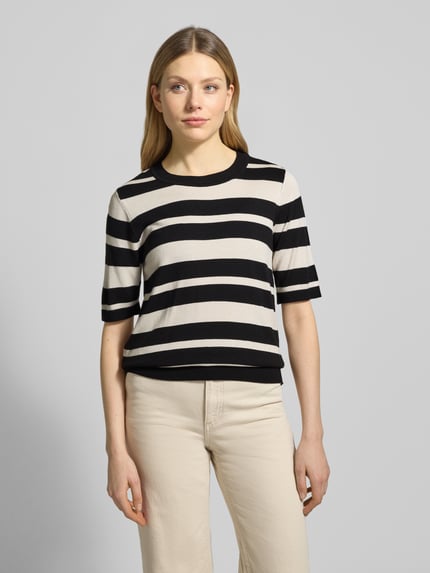Frauenmodel trägt Strickshirt mit Rundhalsausschnitt und Label-Detail von More & More, Viskose-Elasthan-Mix, schwarze und cremefarbene Streifen, Regular Fit, Ganzkörperansicht von vorne.