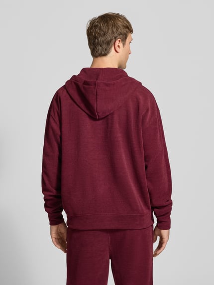 Männermodel trägt Oversized Fit Sweatjacke mit Label-Detail Modell 'Mezzano' von PEGADOR, bordeaux, Material-Mix, Rückenansicht.