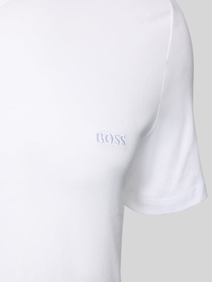 Männermodel trägt T-Shirt mit V-Ausschnitt im 3er-Pack Modell 'Classic' von BOSS aus weißer reiner Baumwolle mit Label-Stitching, Nahaufnahme Oberkörper.