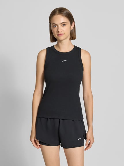 Frauenmodel trägt Slim Fit Tanktop aus Baumwoll-mix von Nike, schwarz mit weißem Logo, glatte Textur, Ganzkörperansicht von vorne, Damen Tanktop von Nike.