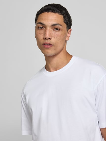 Männermodel trägt Regular Fit T-Shirt mit Rundhalsausschnitt von Jack & Jones aus Reine Baumwolle, weiße Farbe, Nahaufnahme Oberkörper. Herren T-Shirt mit 1/2-Arm, Rückenlänge bei Größe M 70 cm.