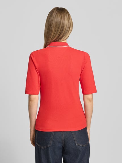 Vrouwenmodel draagt Slim Fit Poloshirt aus Lyocell-Mix van Tommy Hilfiger, rood, uni, korte knoopsluiting, piquéstructuur, logo-stitching, contrasterende kraag, halve mouw, slim fit, rugaanzicht.