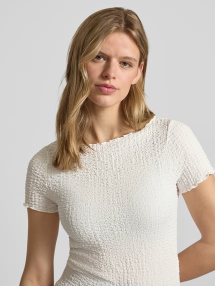 Frauenmodel trägt Slim Fit T-Shirt mit Strukturmuster Modell 'Alora' von Noisy May in Offwhite, U-Boot-Ausschnitt, Nahaufnahme Oberkörper.