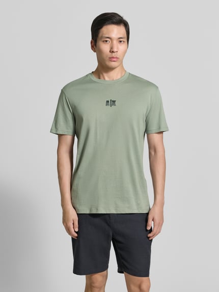 Mannenmodel draagt T-shirt met logo en ronde hals van ARMANI EXCHANGE, puur katoen, regular fit, ruglengte maat M 82 cm, geheelaanzicht voorkant.