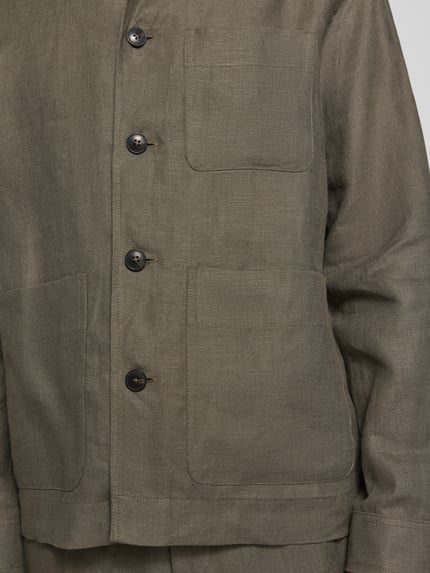 Męski model nosi koszulę wierzchnią Regular Fit Overshirt aus reinem Leinen model 'BAIRD' von SELECTED HOMME, efekt: jednolity kolor, krój regular fit, wykładany kołnierz, listwa guzikowa, długi rękaw, brustasza, nakładana boczna kieszeń, wykończenie materiału: tkanina lniana, materiał: len; detal: zbliżenie na górną część.