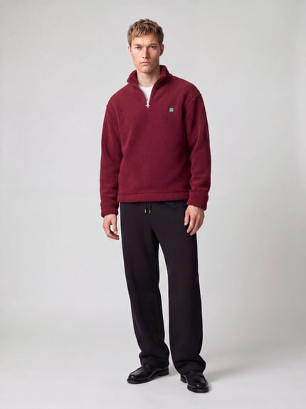 Männermodel trägt Sweatshirt mit Logo-Patch Modell 'Derylong' von HUGO in Bordeaux, strukturierte Fleece-Optik, Ganzkörperansicht von vorne.