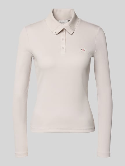 Frauenmodel trägt Slim Fit Langarmshirt aus Baumwoll-Mix von Calvin Klein Jeans in Creme mit feiner Struktur und kleinem Logo, Ganzkörperansicht von vorne.