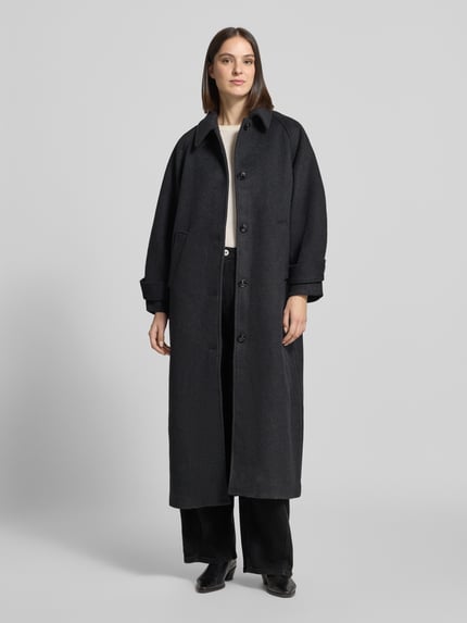 Frauenmodel trägt Mantel aus Leinen-Mix mit Stehkragen Modell 'Keaton' von Neo Noir, dunkle Farbe, Knopfleiste, Eingrifftaschen, Ganzkörperansicht von vorne.