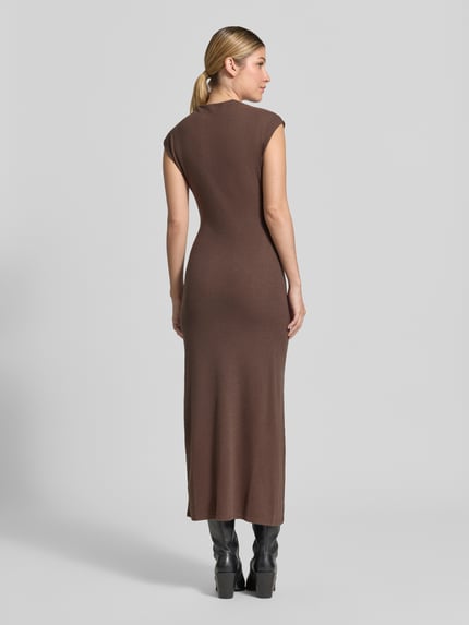 Frauenmodel trägt Maxikleid mit Raffungen Modell 'BASILA' von MANGO in Braun, figurbetonter Schnitt, Seitenschlitz, Ganzkörperansicht Rückansicht. Material-Mix mit Viskose-Anteil, Rückenlänge 136 cm, Brustweite 39 cm.