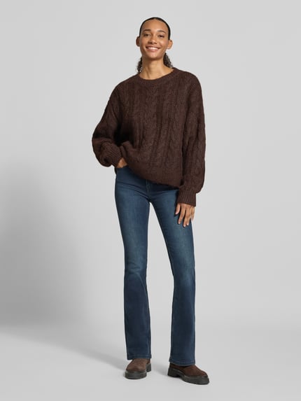 Frauenmodel trägt Oversized Fit Strickpullover mit Zopfmuster von REVIEW in Dunkelbraun, Rundhalsausschnitt, elastische Abschlüsse, Ganzkörperansicht von vorne.