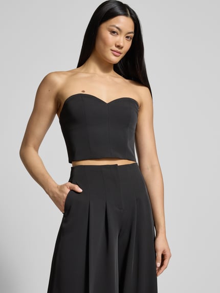 Kobiece model nosi Slim Fit Top im schulterfreien Design od Jake*s Cocktail, czarny, gładka tekstura, herzausschnitt, ujęcie całej sylwetki z przodu.