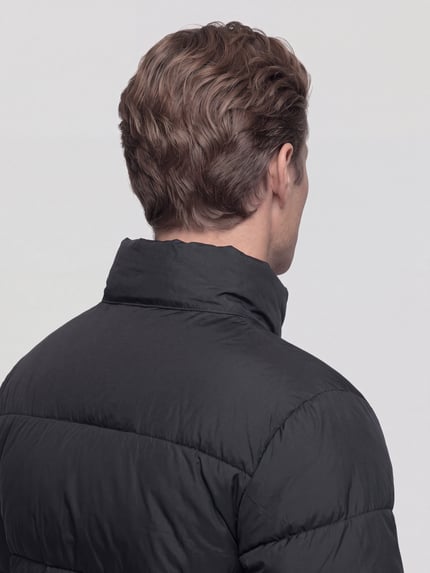 Männermodel trägt Steppjacke mit hohem Stehkragen Modell 'ONSMAVERICK' von ONLY in einfarbigem Schwarz mit Struktur, Ganzkörperansicht Rückansicht.