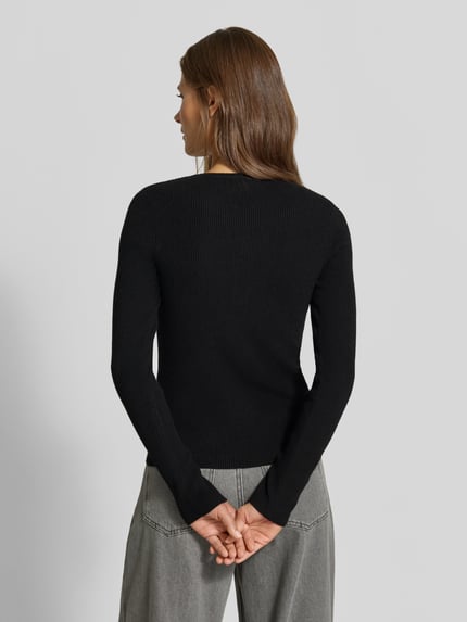 Frauenmodel trägt Slim Fit Longsleeve in Strick-Optik von MYON, schwarz, feine Struktur, Henley-Ausschnitt, Ganzkörperansicht Rückansicht.