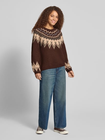 Frauenmodel trägt Pullover mit Jacquardpasse von ONLY in Strickoptik, melange, geometrisches Rautenmuster, Rundhals, Ganzkörperansicht von vorne.
