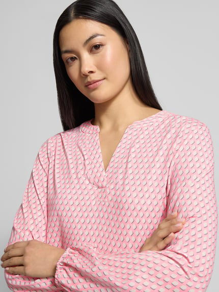 Vrouwenmodel draagt Longsleeve met V-Ausschnitt van Smith and Soul in roze-wit geometrisch patroon, katoen-viscose-mix, losse pasvorm, Nahaufnahme bovenlichaam.