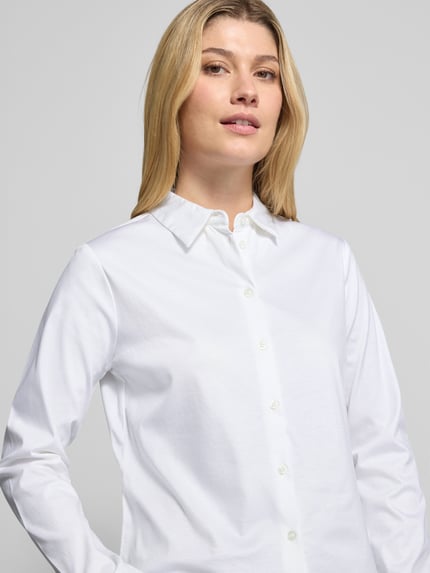 Frauenmodel trägt Regular Fit Bluse aus Baumwolle von Christian Berg Woman, weiß, Hemdblusenkragen, Knopfleiste, Nahaufnahme Oberkörper. Rückenlänge bei Größe 36: 60 cm, reine Baumwolle.