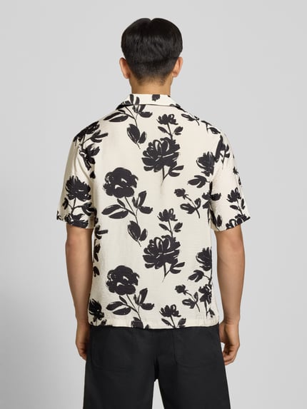 Männermodel trägt Regular Fit Freizeithemd aus Viskose-Mix von REVIEW, creme mit schwarzen Blumen, Reverskragen, 1/2-Arm, Knopfleiste, Rückenlänge 74 cm, Schulterbreite 54 cm, Ärmellänge 30 cm, Ganzkörperansicht Rückansicht.