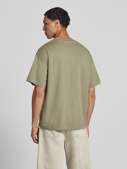 Männermodel trägt Herren T-Shirt mit Rundhalsausschnitt Modell 'BARRON' von Jack & Jones, Baumwoll-Mix mit Stretch-Anteil, Relaxed-Fit, Rückenlänge bei Größe M 73 cm, dezentes Beige, glatte Textur, Ganzkörperansicht Rückansicht.