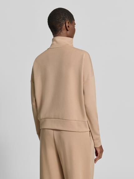 Frauenmodel trägt Troyer mit Stehkragen und Reißverschluss von Christian Berg Woman in Beige, glatte Textur, Ganzkörperansicht Rückansicht. Material-Mix mit Modal-Anteil, Regular Fit