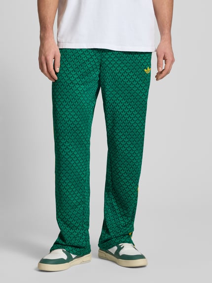 Männermodel trägt grüne Sweatpants mit elastischem Bund von adidas Originals, lockerer Schnitt, Eingrifftaschen, Label-Stitching, Nahaufnahme Unterkörper.